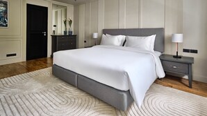 A modern bedroom with a large bed, bedside tables, and a decorative mirror. - Floral Court Hotel and Residence (Bangkok)