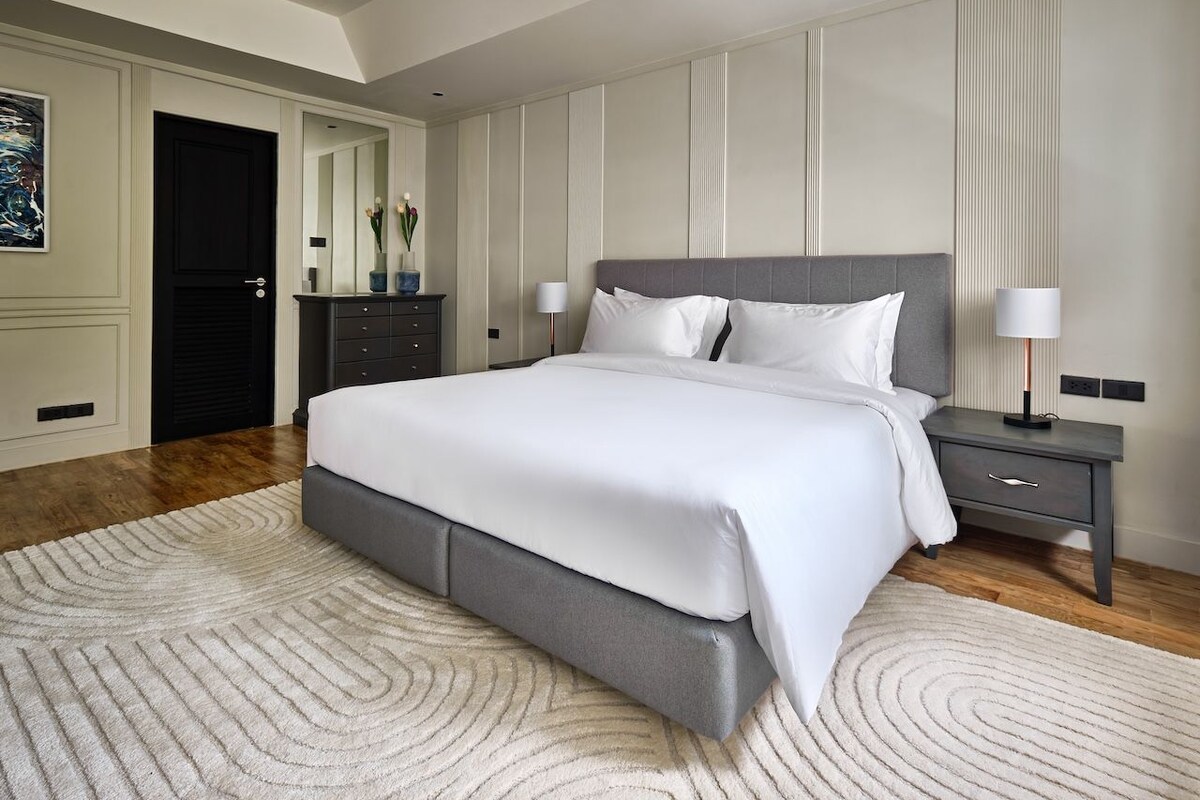 A modern bedroom with a large bed, bedside tables, and a decorative mirror.