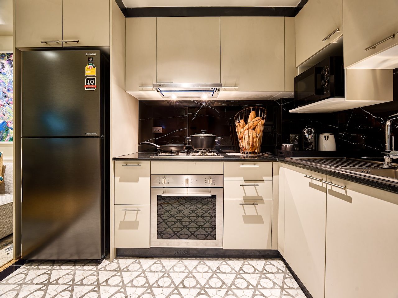A modern kitchen with a stainless steel refrigerator, a built-in oven, and a microwave.