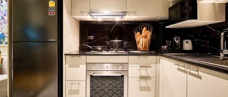 A modern kitchen with a stainless steel refrigerator, a built-in oven, and a microwave.