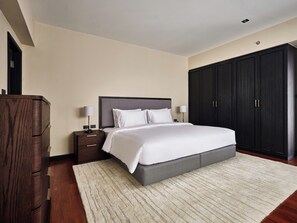 A bedroom with a bed, bedside tables, a wardrobe, and a carpet. - Floral Court Hotel and Residence (Bangkok)