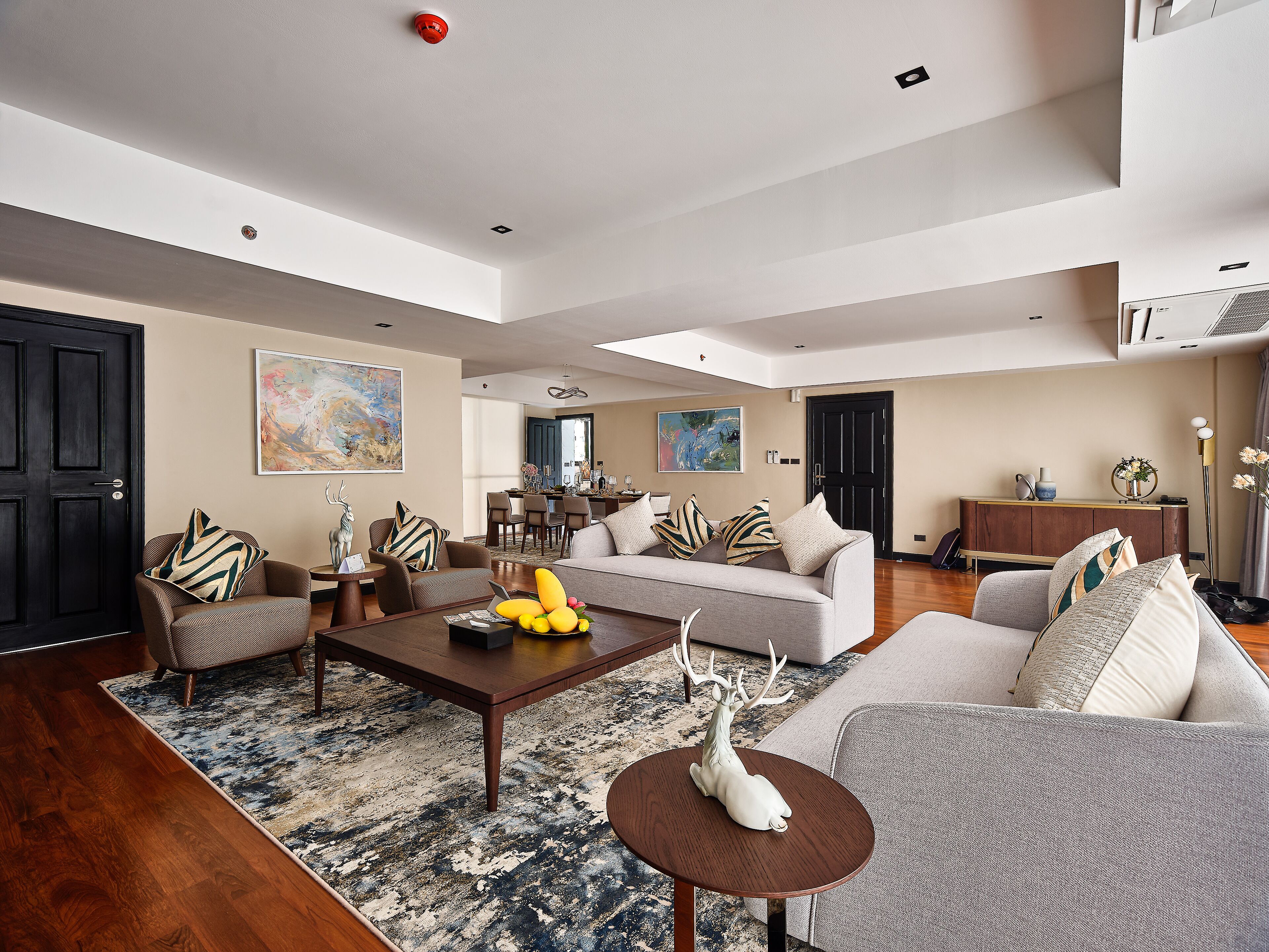 Ein großzügiges Wohnzimmer mit einer breiten Couch, einem Couchtisch und einem Essbereich im Hintergrund.