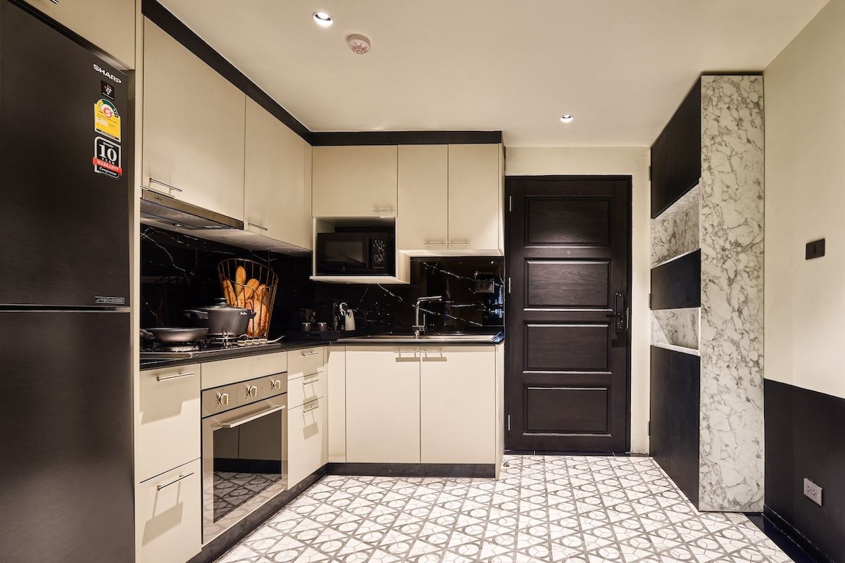 A modern kitchen with white cabinets, a black refrigerator, and a patterned floor.