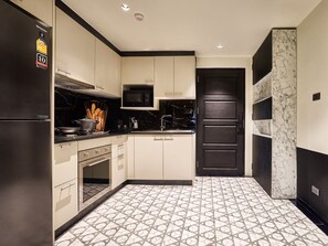 A modern kitchen with white cabinets, a black refrigerator, and a patterned floor. - Floral Court Hotel and Residence (Bangkok)