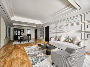 A modern living room with a sofa, coffee table, and houndstooth patterned chair. - Floral Court Hotel and Residence (Bangkok)