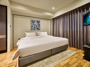 A hotel room with a large bed, a flat-screen TV, and a painting on the wall. - Floral Court Hotel and Residence (Bangkok)