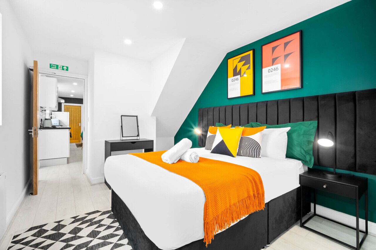 Ein modernes Hotelzimmer mit einem großen Bett, einem Nachttisch, einem Schreibtisch und einer Wand in Grüntönen.
