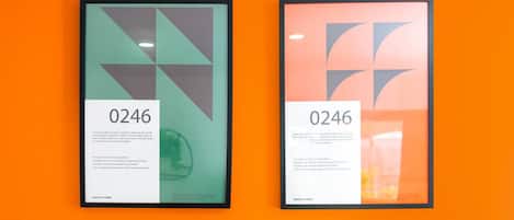 Dos obras de arte enmarcadas con el número 0246 sobre una pared de color naranja brillante.
