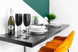 A modern dining table with a bottle of Prosecco, two black wine glasses, and white plates. - Luxury 3 Bedroom Apartment- Terrace (Birmingham)