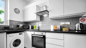 Une cuisine moderne équipée d’un lave-linge, d’un four, d’un four à micro-ondes et d’un panneau indiquant qu’il est interdit de fumer.