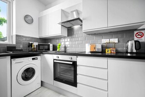 A modern kitchen with a washing machine, oven, microwave, and a no-smoking sign. - Luxury Apartment  - WiFi (Birmingham)