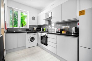 Una cocina moderna con armarios blancos, lavadora, microondas y estufa.