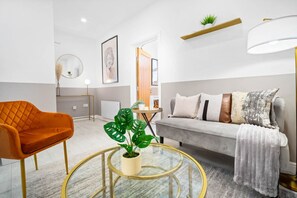 A modern living room with a sofa, a round coffee table, a chair, and a potted plant. - Luxury Apartment  - Patio - Smart TV - Netflix (Birmingham)
