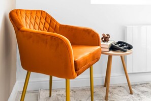 A room with a single orange chair, a small wooden table, and a radiator. - Luxury Apartment  - Patio - Smart TV - Netflix (Birmingham)