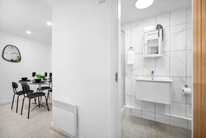 A modern bathroom with a white sink, mirror, and tiled walls.