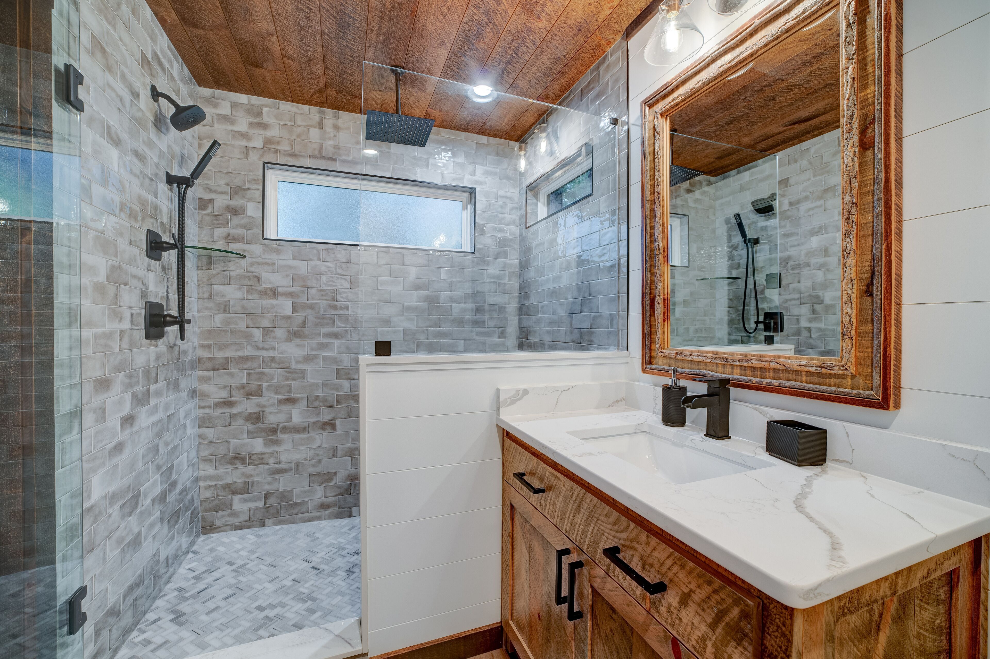 A modern bathroom with a glass shower enclosure, a large mirror, and a wooden vanity.