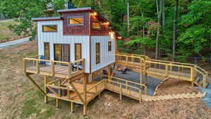 A cabin with a deck, a fire pit, and a small outdoor seating area. - Cozy Couples Treehouse w Hot Tub, Fire Pit, Pet Friendly, Lake Access (Morganton)