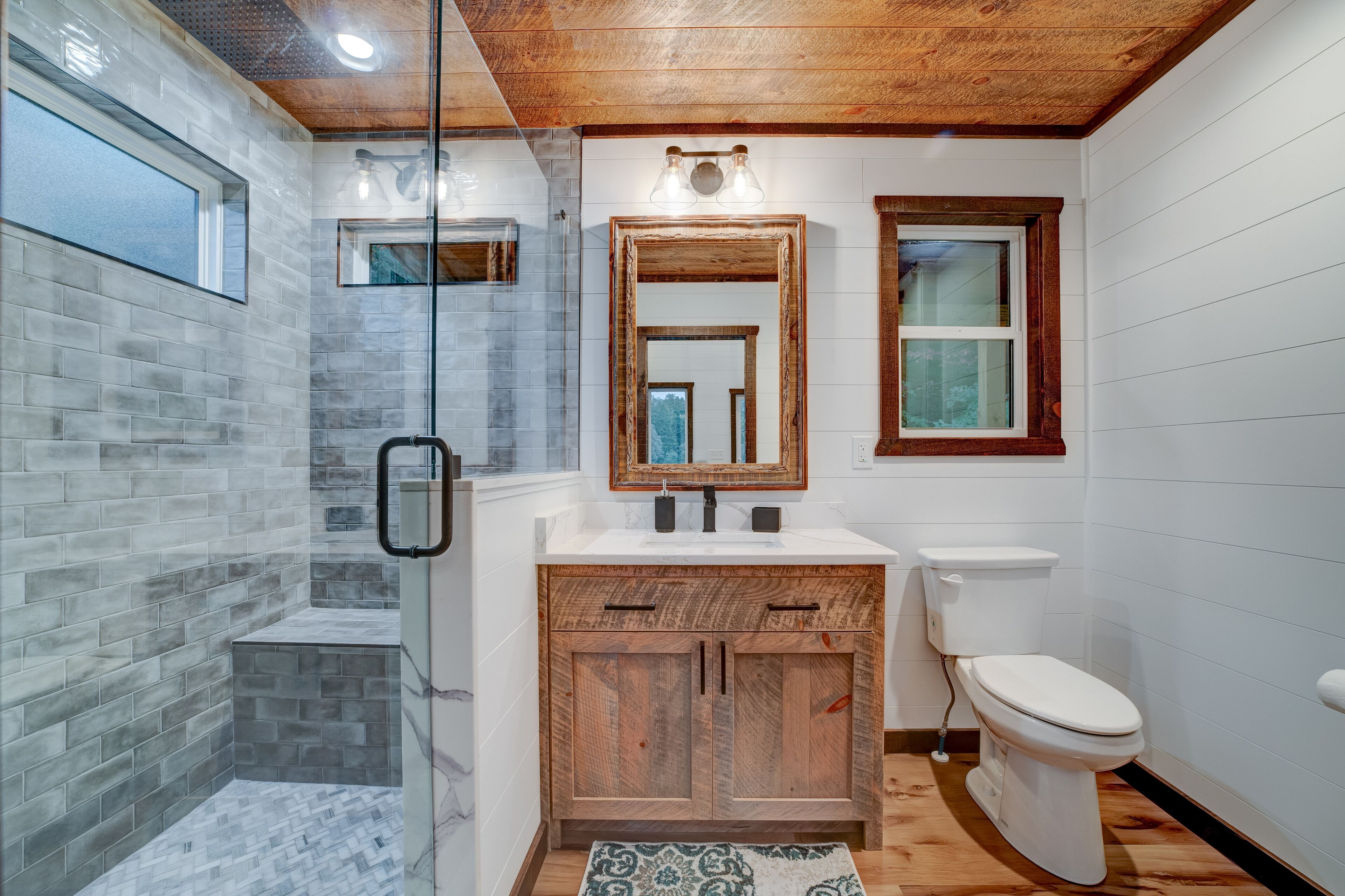 Ein modernes Badezimmer mit Dusche, einem Holzkosmetikschrank, einer Toilette und einem großen Spiegel.