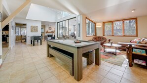 Un amplio salón con mesa de billar, un sofá y una mesa de centro.