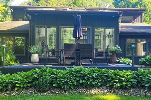 Une maison moderne dotée d’un patio couvert, de mobilier d’extérieur et d’un jardin bien entretenu.