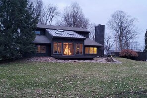 Une maison moderne avec un toit en pente, de grandes fenêtres et une pelouse bien entretenue.