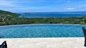 On peut admirer une piscine depuis laquelle on a une vue dégagée sur la mer et un paysage verdoyant.