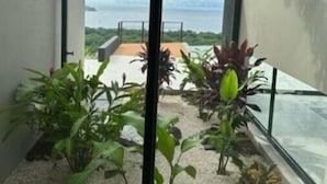 Un intérieur moderne donnant sur un balcon, avec des plantes et un ciel dégagé.