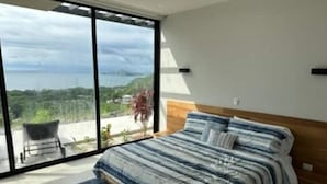 Une chambre dotée d’une grande porte-fenêtre coulissante donnant sur un balcon avec vue sur la mer.