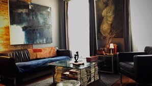 Un salon moderne avec un canapé, une table basse en verre et une bibliothèque.