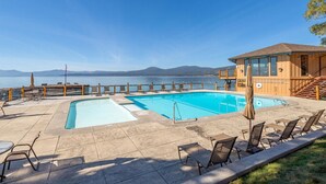 Un espace piscine avec vue sur la mer, des chaises longues et un bâtiment en bois.
