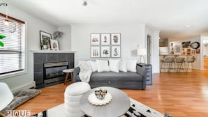 Un salon moderne avec un canapé gris, une table basse ronde et une cheminée.