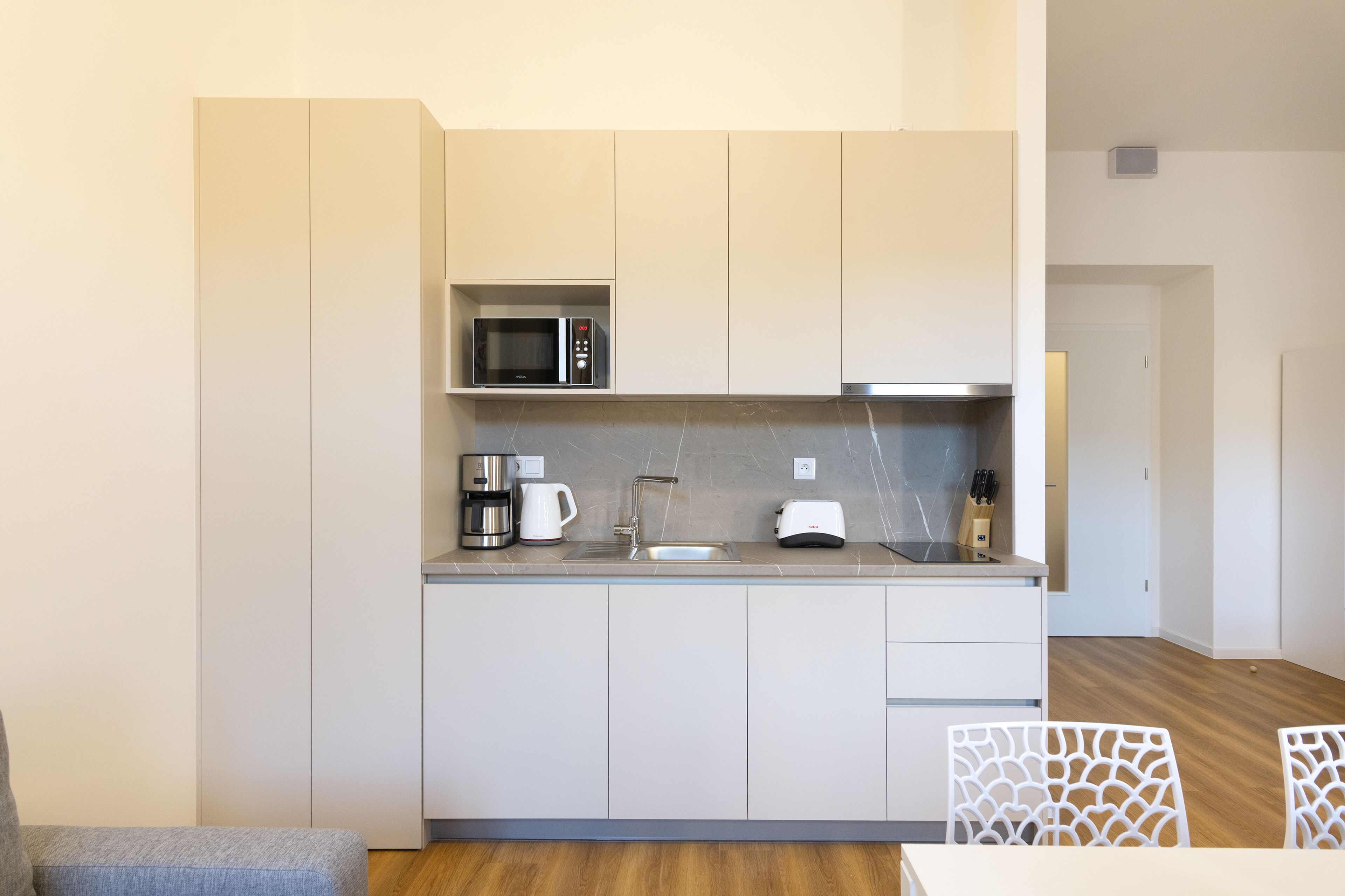 A modern kitchen with white cabinets, a microwave, a coffee maker, and a toaster.