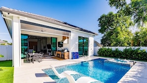 Una casa moderna con piscina, un patio cubierto y un césped bien cuidado.