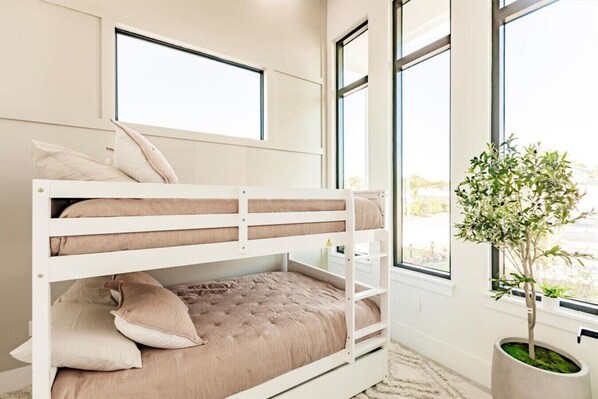 A bunk bed with a window above it, a potted plant, and a view of the outdoors.