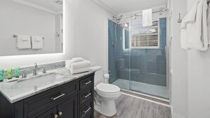 Ein modernes Badezimmer mit einem großen Spiegel, einem мраморной Waschbecken, einer Toilette und einer Duschkabine.