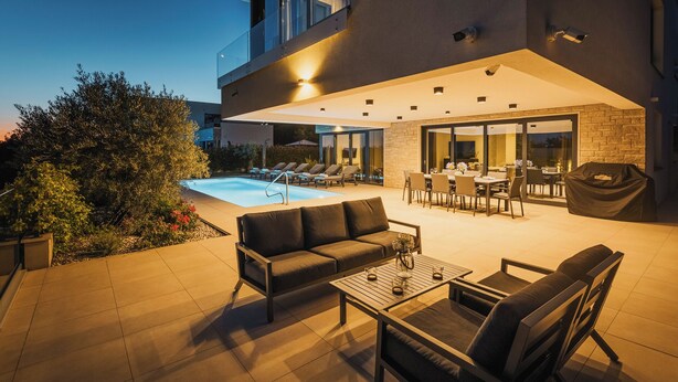 Un patio extérieur moderne doté d’une piscine, d’un espace salon et d’un coin repas.