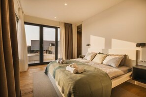 A modern hotel room with a large bed, a nightstand, and a view through a sliding glass door to an outdoor area. - Luxury 4BD villa for 8 with pool, jacuzzi, sauna, gym, bocci and basketball (Brnobići)