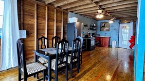 Un comedor amplio con techo de madera y ventiladores, una cocina al fondo y vistas al exterior.