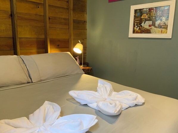 A hotel room with a bed, a nightstand with a lamp, and a framed picture on the wall. - Brand NEW Home Over on the Water (Bocas del Toro)