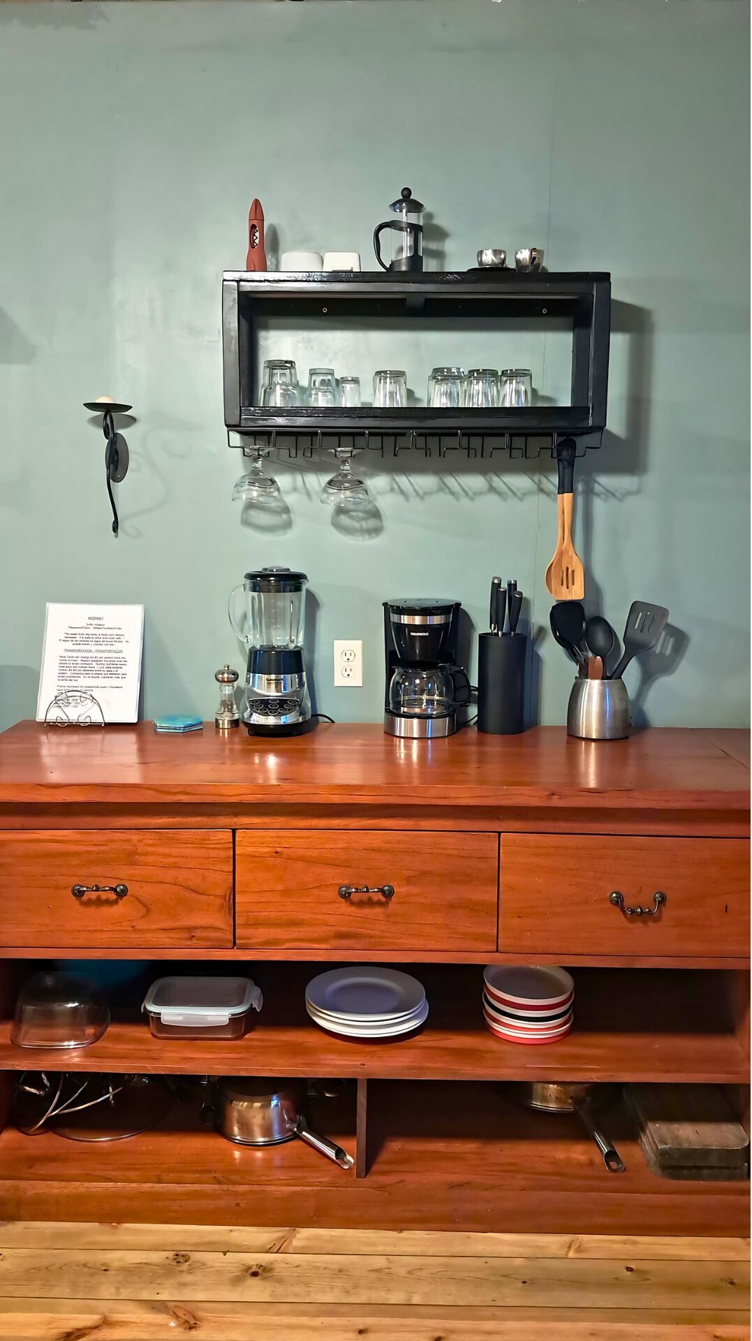 Un plan de travail de cuisine avec une machine à café, un mixeur et une cafetière. On y trouve également des assiettes et un jeu de couteaux.