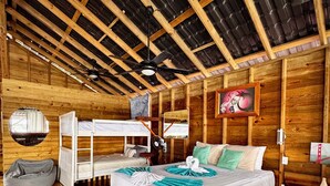 Una baita in legno con un letto a castello, un letto singolo e una ventola a soffitto.
