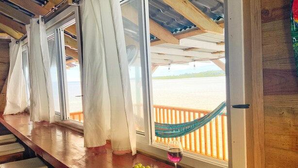 Un bancone in legno con vista sulla spiaggia e un'amaca.