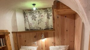 Une pièce avec deux lits en bois, une armoire en bois et une petite bibliothèque.