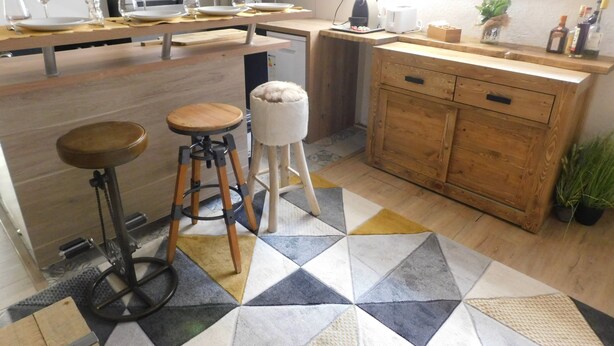 Une cuisine avec un plan de travail en bois, des tabourets, un évier et un sol à motifs.