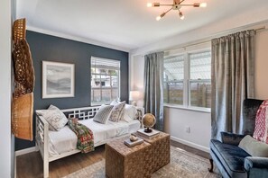 A modern living room with a white sofa, a coffee table, and a blue armchair. There are two windows with curtains, a globe on the coffee table, and a wall-mounted lamp. - House of Rio, Seaside Getaway (Jensen Beach)