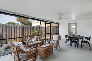 A sunlit patio with wicker furniture, a dining table, and chairs. - House of Rio, Seaside Getaway (Jensen Beach)