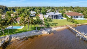 A residential area with houses, a swimming pool, and a dock extending into a body of water. - House of Rio, Seaside Getaway (Jensen Beach)