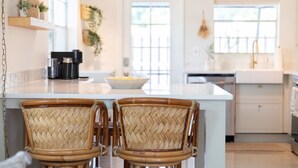 A kitchen with a large island, wicker chairs, and a hanging light fixture. - House of Rio, Seaside Getaway (Jensen Beach)