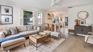 A spacious living room with a sofa, coffee table, and a dining area with chairs. - House of Rio, Seaside Getaway (Jensen Beach)