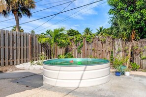 A round above-ground pool with a wooden fence and tropical plants in the background. - House of Rio, Seaside Getaway (Jensen Beach)